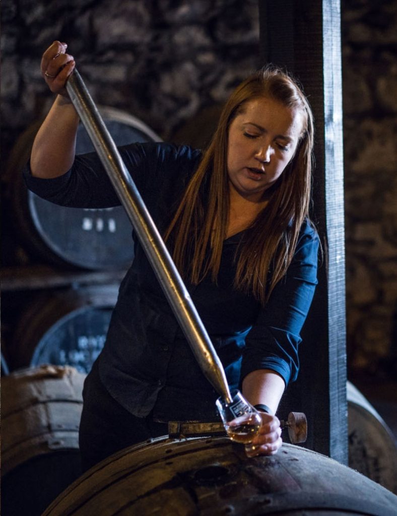 A section of whisky being taken out of a cask and put into a glass by a lady with long hair