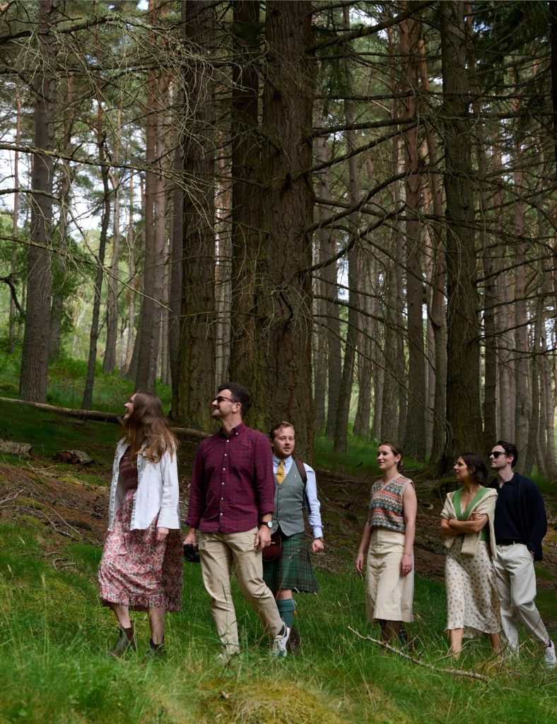 A ghillie taking a group of five guests on a woodland walk with trees in the background