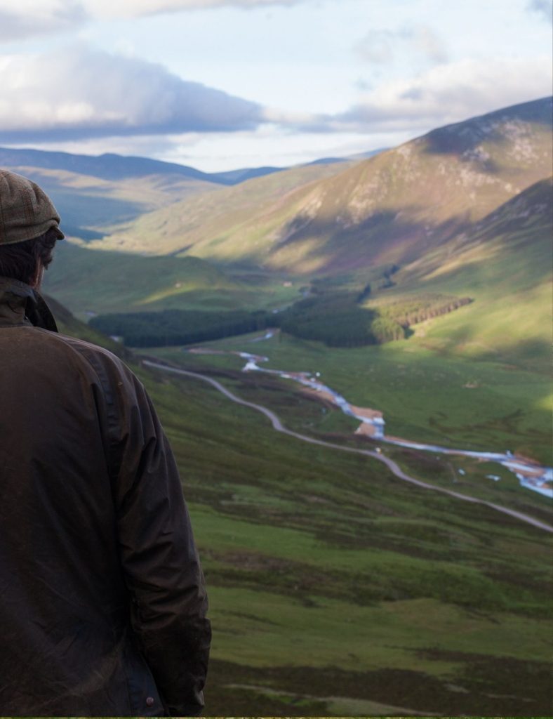 A view of the mountains and river dee with sun shining on the hills with a man stood on the edge