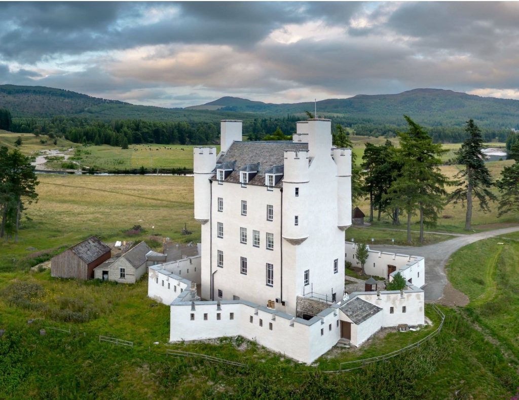 a Birdseye view of Braemar Castle, with moody sky and rolling hills