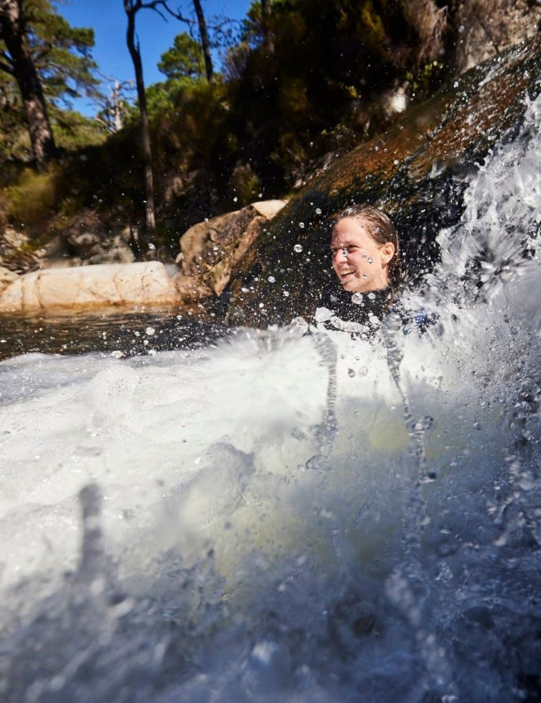Annie Armstrong wild swimming with water splashing around her.