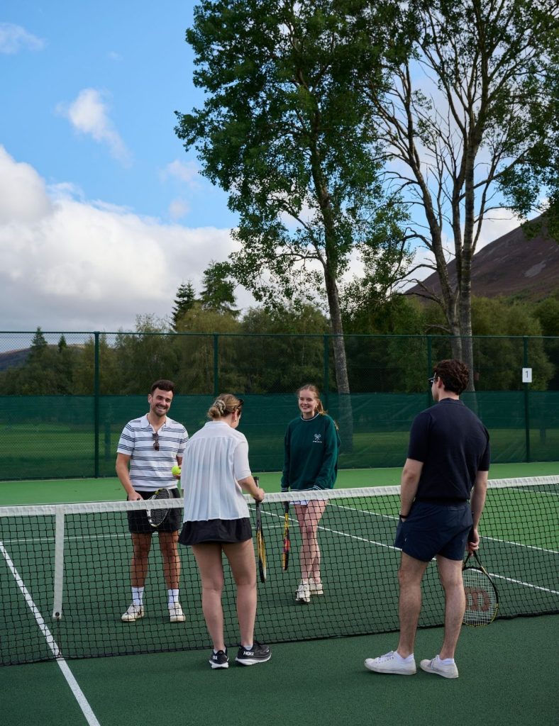 Guests playing tennis at the tennis courts with blue skies.