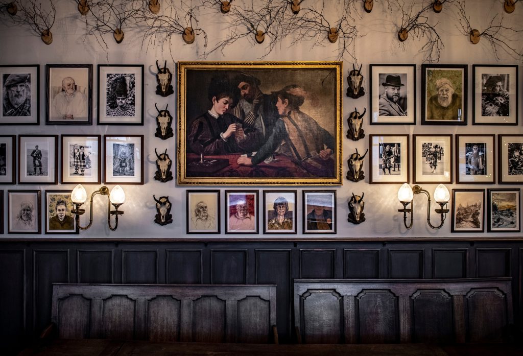 An oil painting of figures playing cards surrounded by smaller portrait paintings