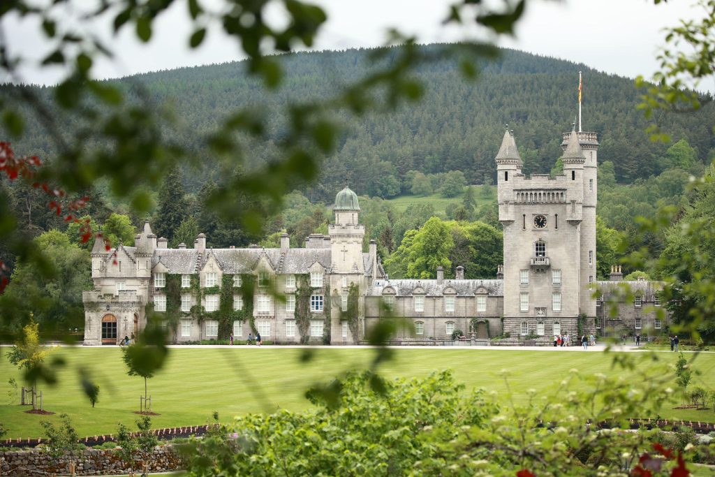 Balmoral castle shot from a distance with a green lawn in the foreground.