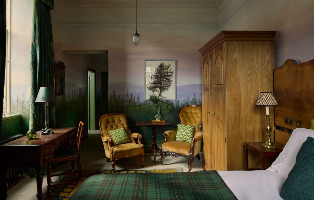 Yellow velvet chairs and a bed in the Pine Wood room with walls painted in a colourful forest mural