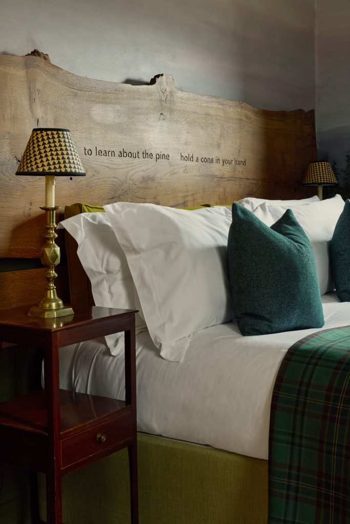The bed with a rustic wooden headboard in the Pine Wood Nature and Poetry room