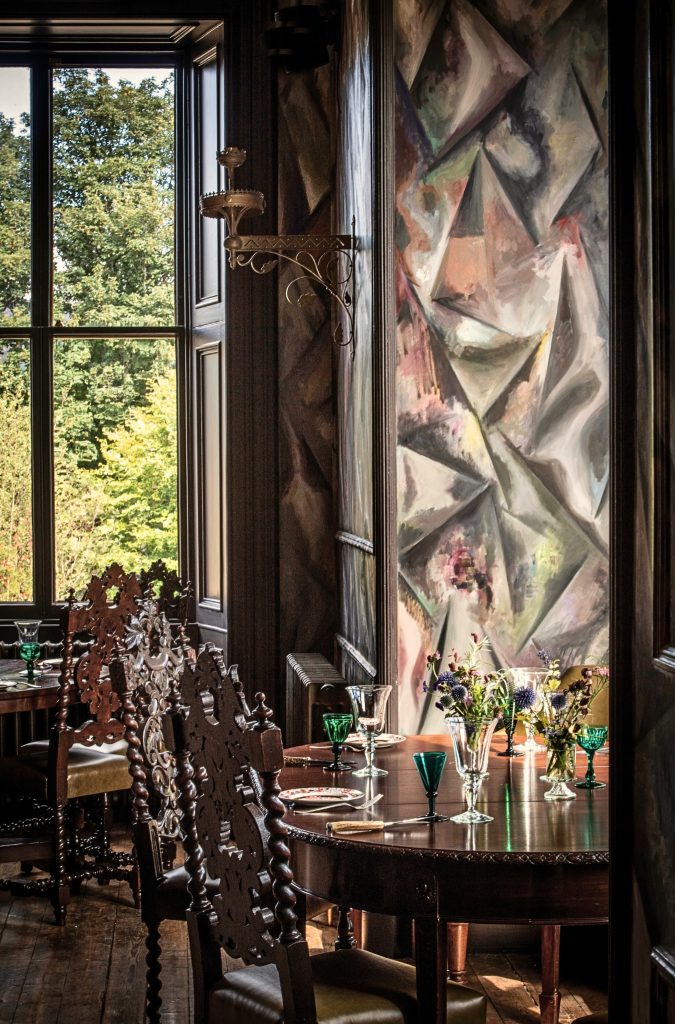 The wall mural beside a window with wooden tables in The Clunie Dining Room