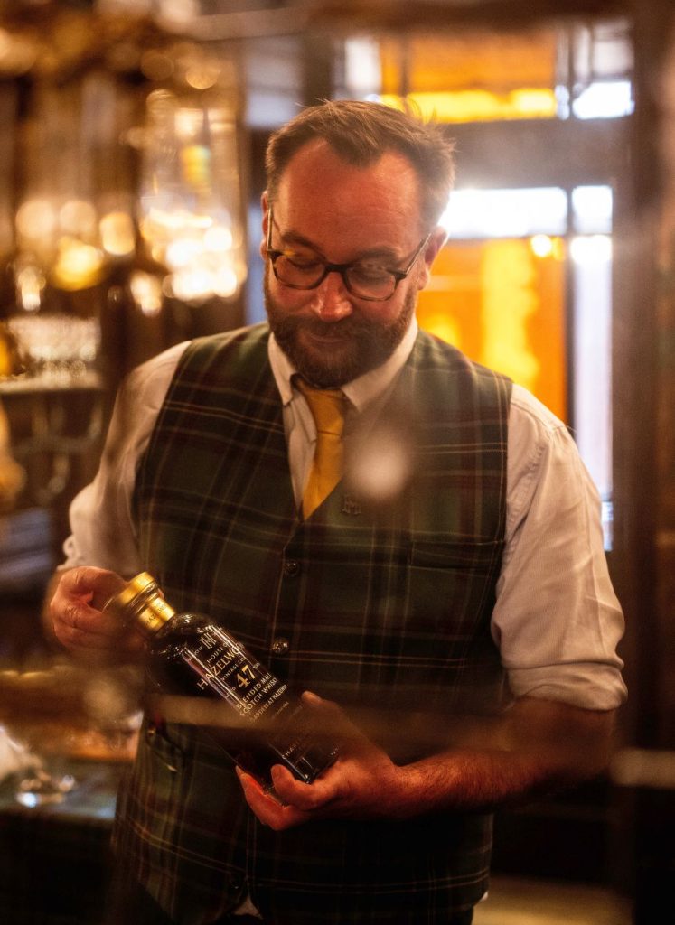 Tom Addy holding a bottle of whisky from the House of Hazelwood collection.