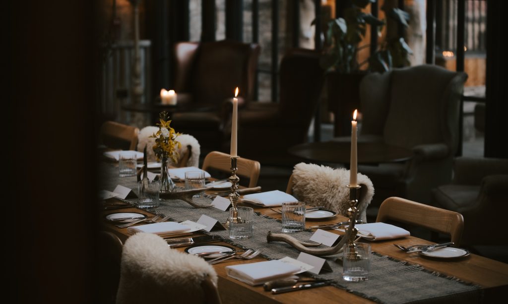 A table set for a special event with candles lit and sheepskins over the chairs