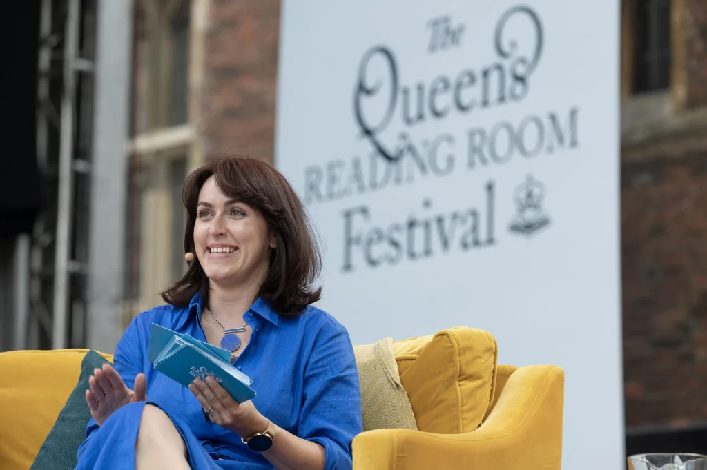 Lady with brown hair on stage sitting on yellow armchair