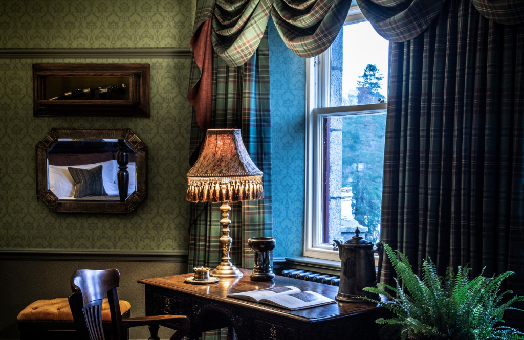 The Highlander suite desk beside a window with tartan curtains