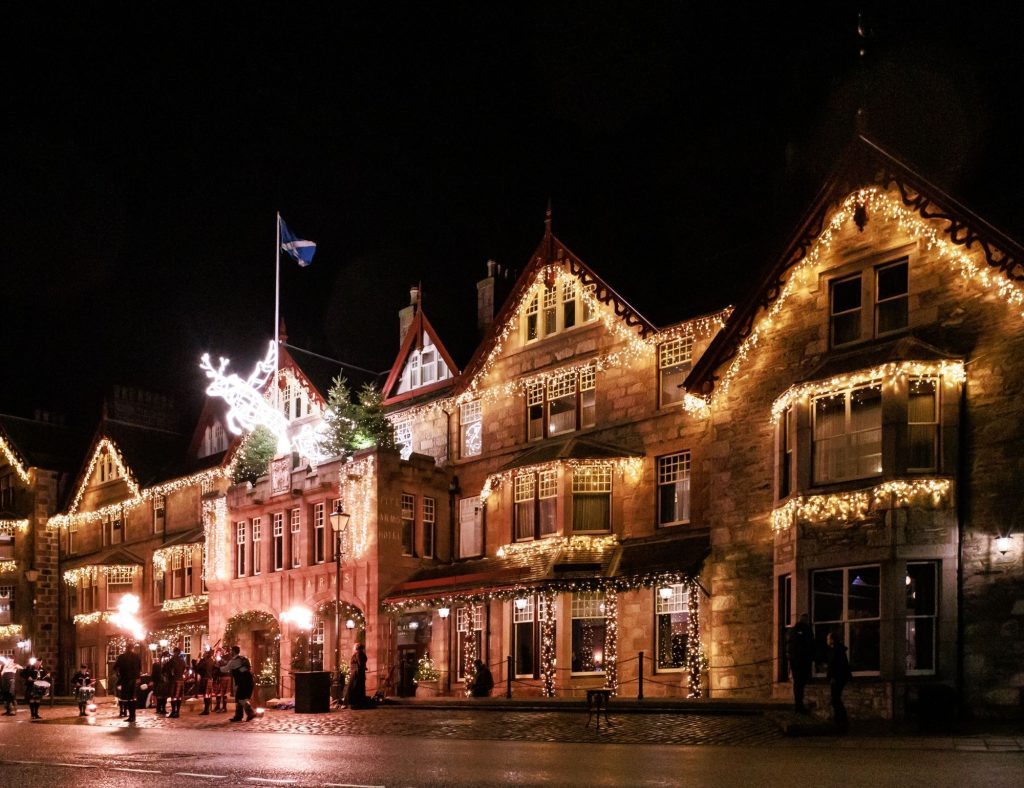 The exterior of the Fife Arms hotel at night, lit up with lights running along the hotel.