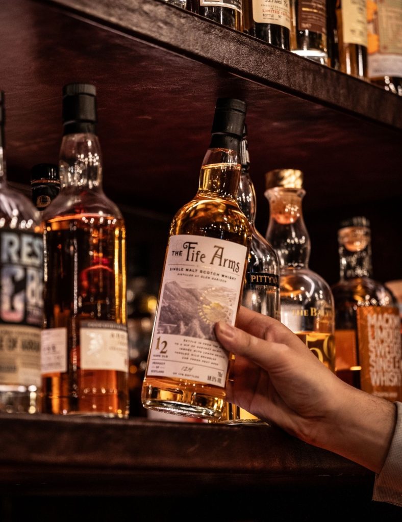 The Fife Arms whisky being taken off the shelf in Bertie's Whisky Bar.