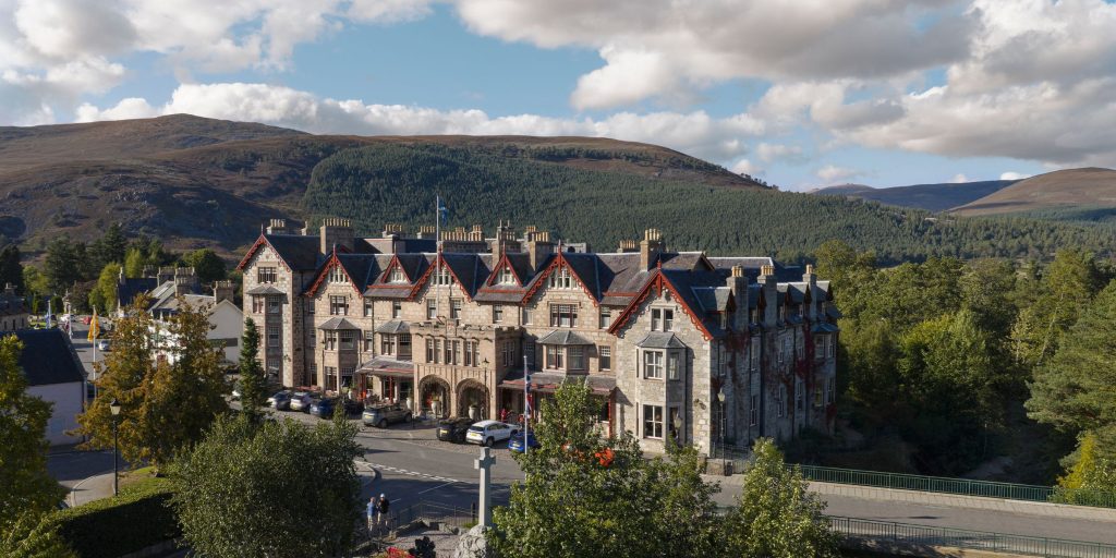 Drone shot of the exterior of the fife arms hotel, with mountains in the background
