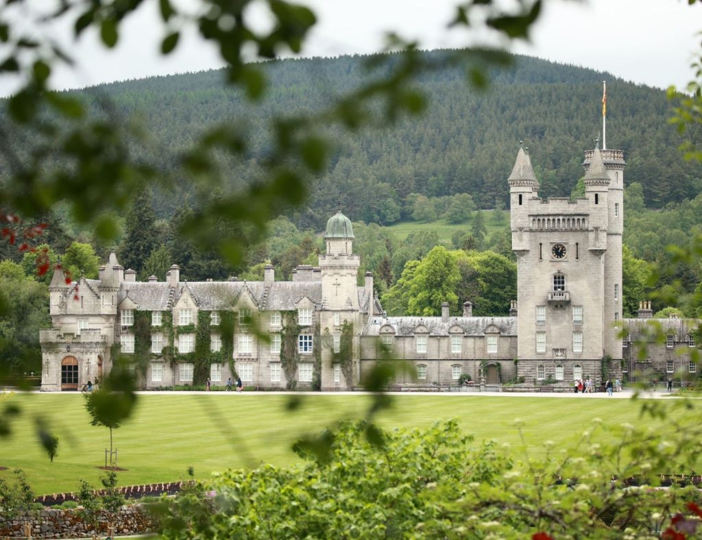 The front of Balmoral Castle with a large lawn in the foreground and trees behind the castle