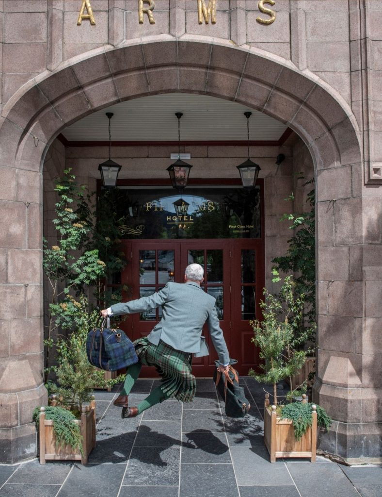 Jumping ghillie outside the fife arms hotel carrying two bags