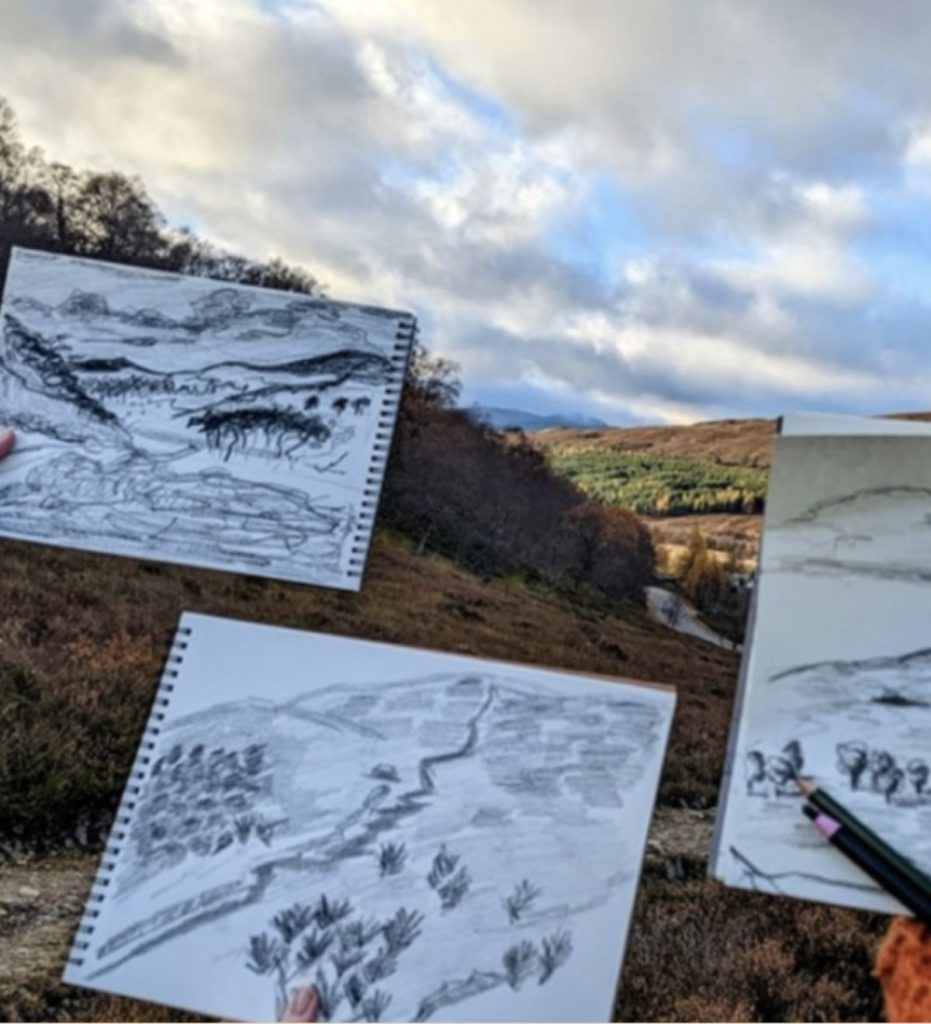 Guest landscape sketches photographed with landscape in the background.