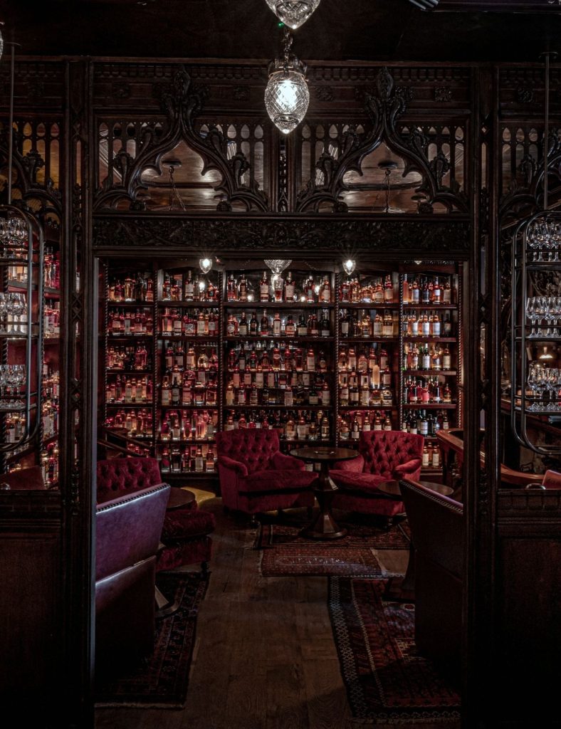 Bertie's whisky bar with red armchairs and whiskies on display.