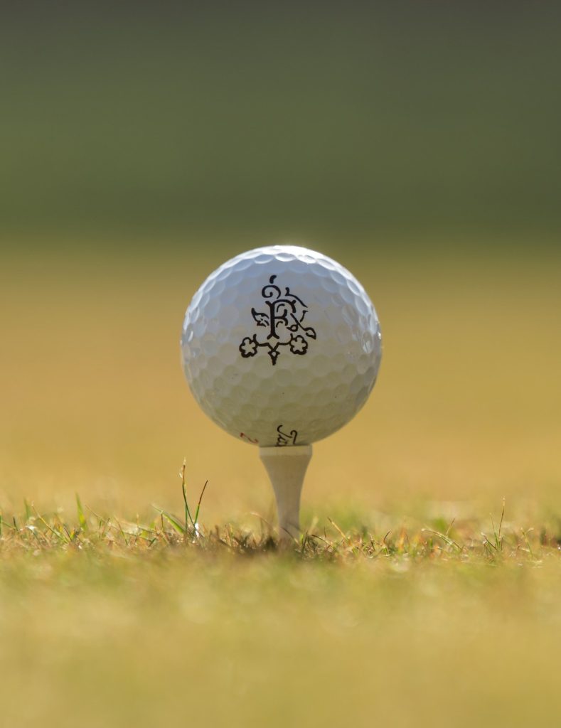 A Fife Arms branded golf ball set up on a tee on grass.