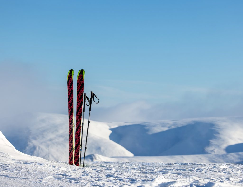 Skis and poles standing upright on a snowy mountain top.
