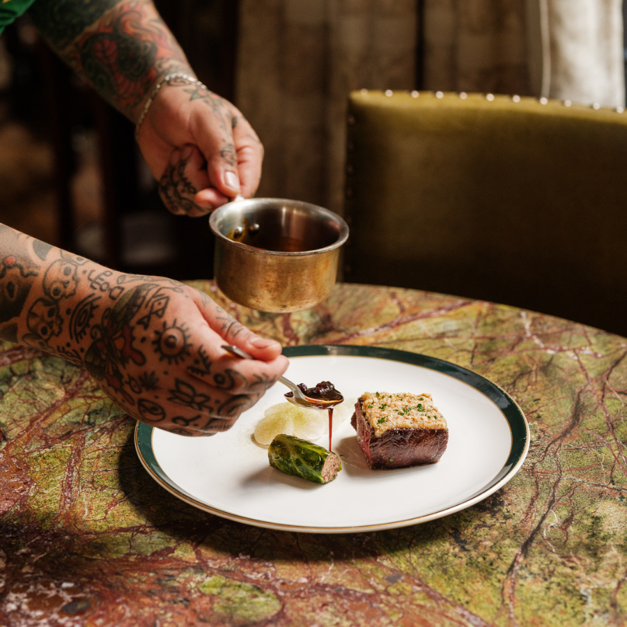 A chef spooning sauce onto a dish.