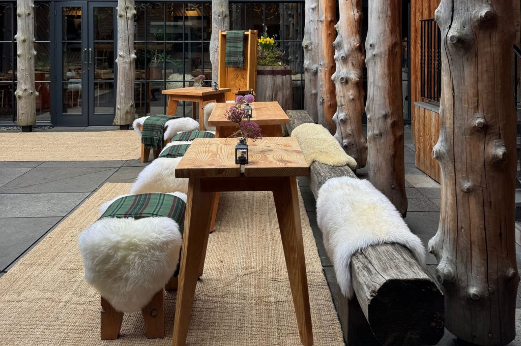 Wooden seating with sheepskins and tartan throws in a courtyard.