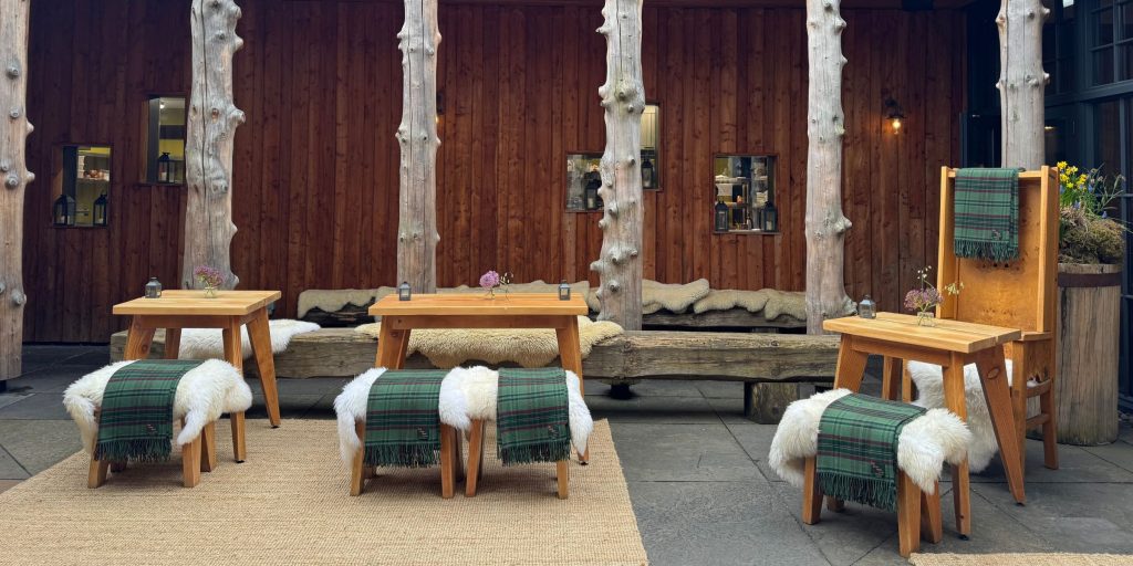 Sheepskin throws and tartan blankets on chairs and benches in a courtyard dining space