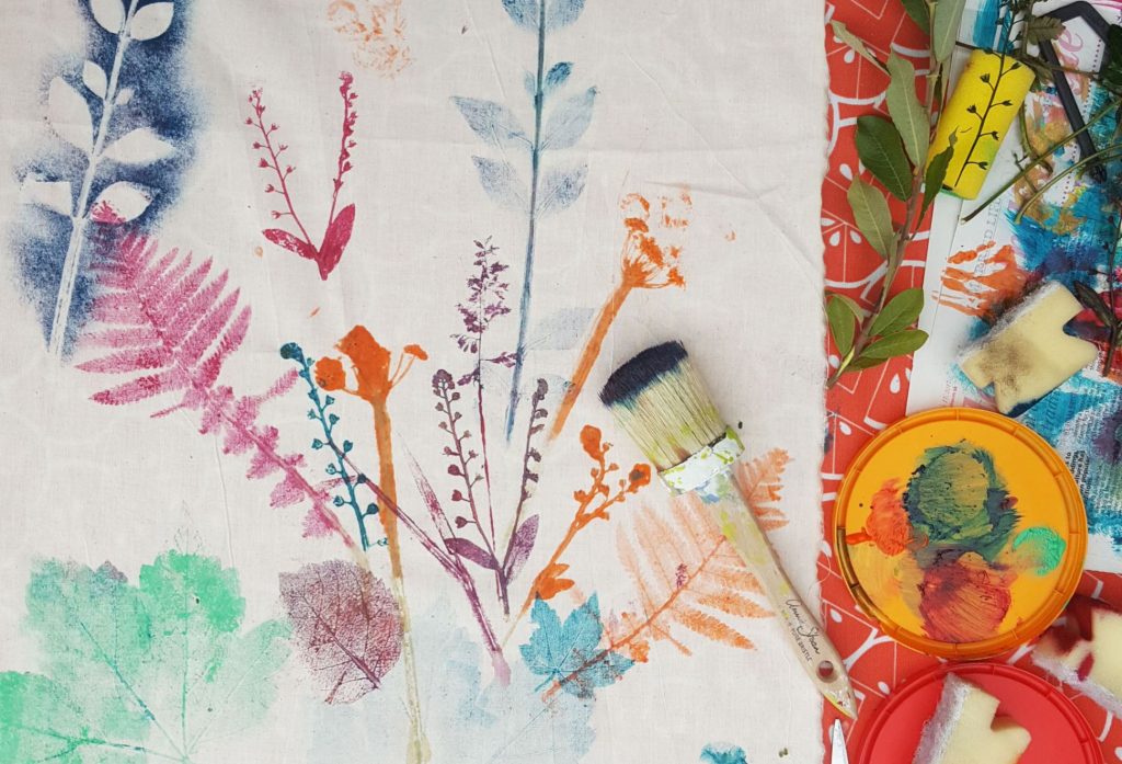 Colourful leaf prints on fabric and a paintbrush