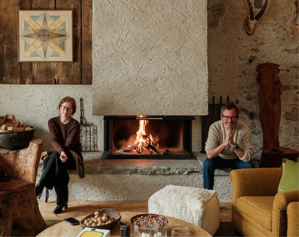 Cozy living room with a man and woman sat either side of a modern fireplace.