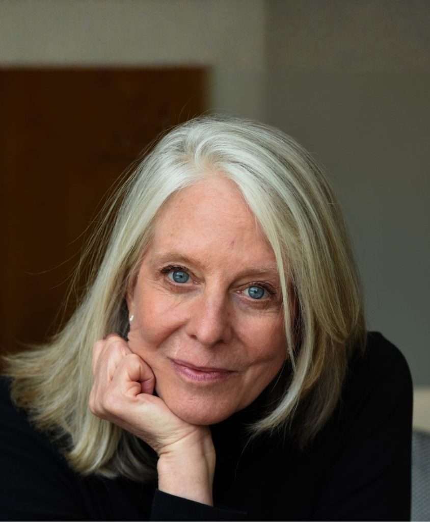 A woman wearing black with straight grey hair.