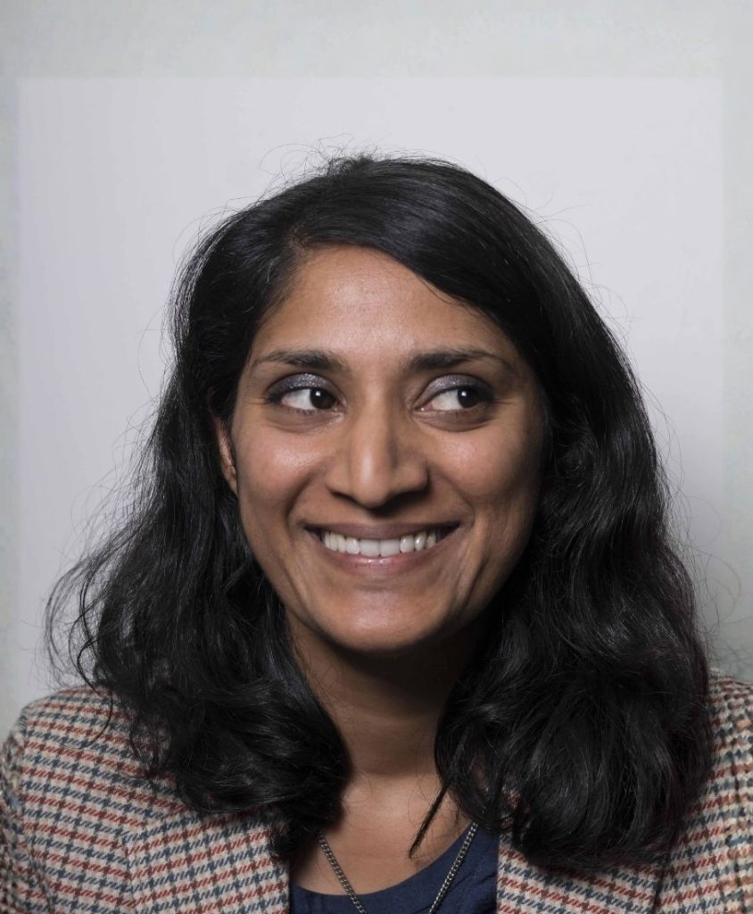 a headshot of a south-asian woman with dark brown hair smiling.