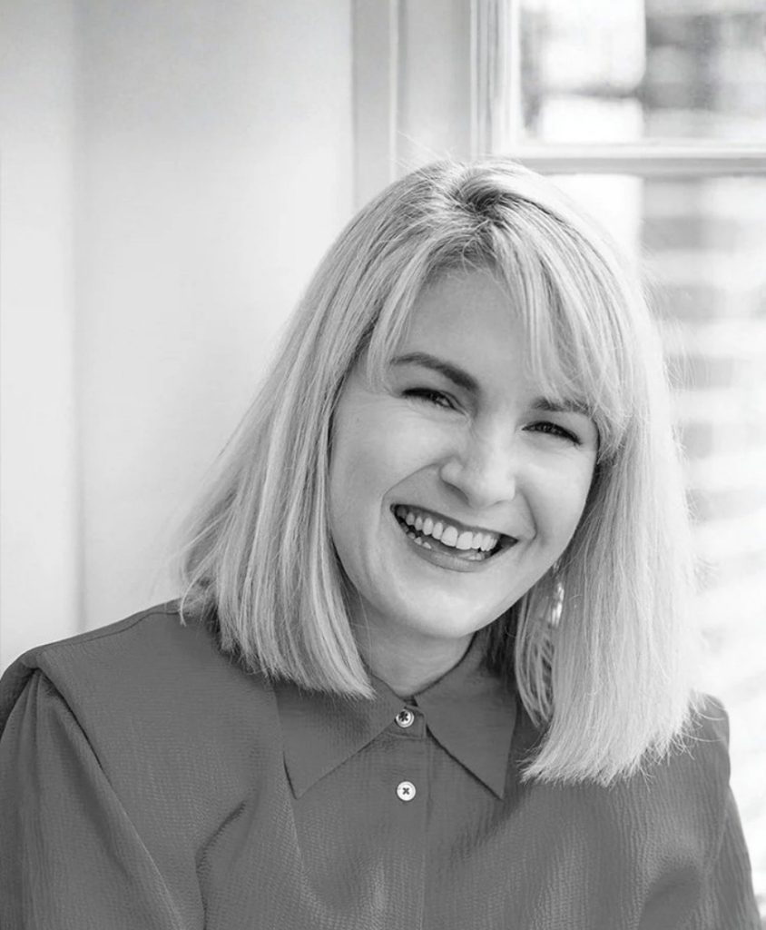 A smiling woman with a straight bob in black and white