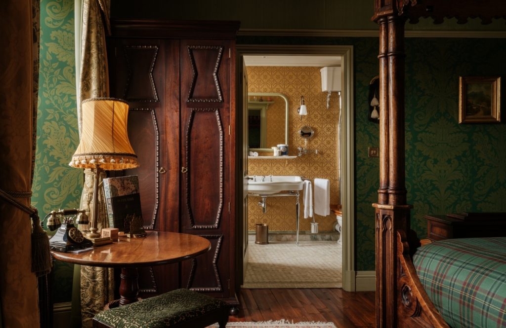 A view through to a bathroom in an opulent green bedroom