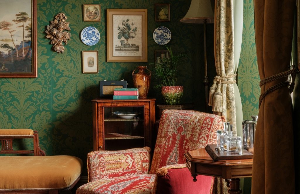 An armchair in a green room decorated with ceramics and artworks