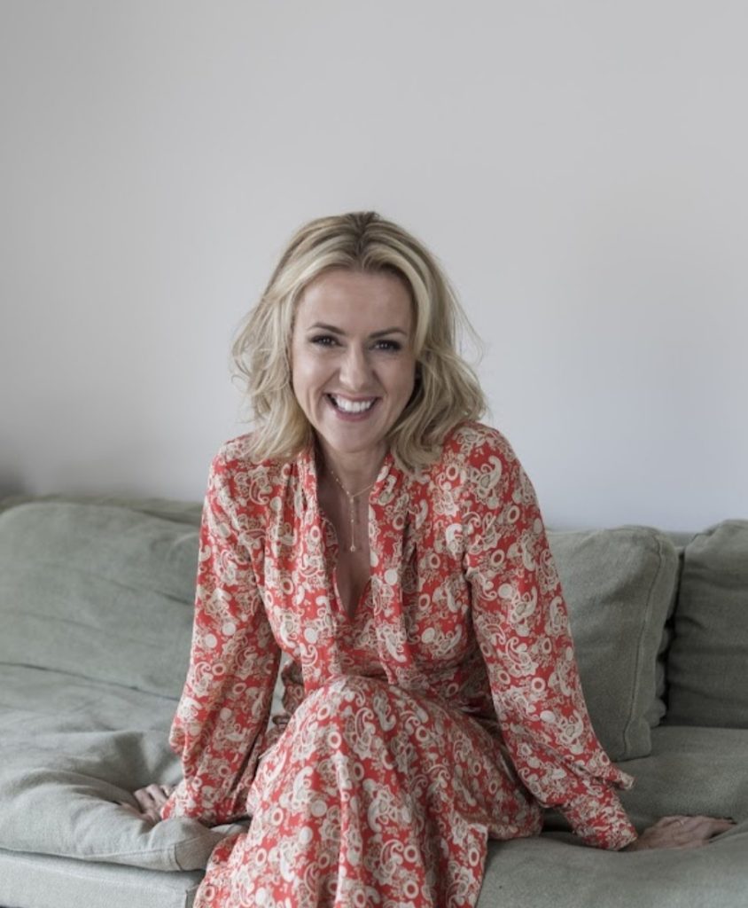 A smiling blonde woman wearing a red patterned dress