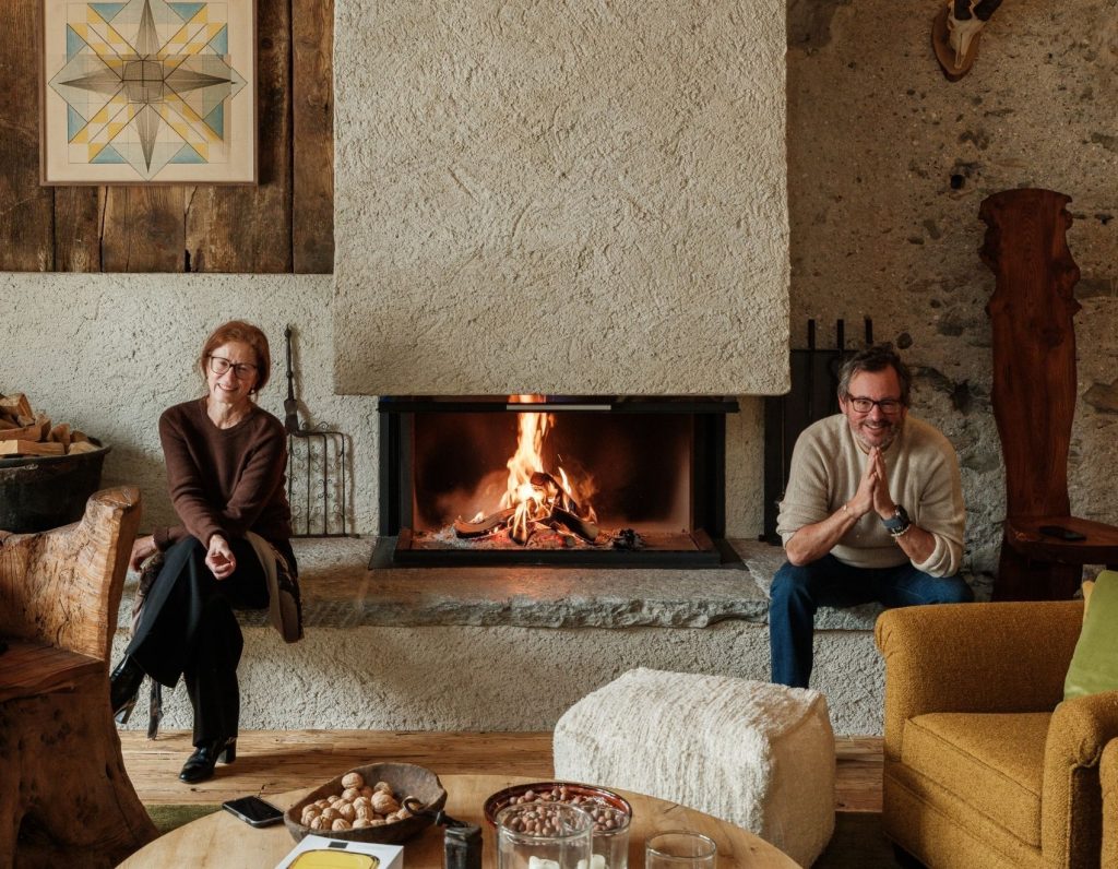 A man and woman sat either side of a modern fireplace in a living room
