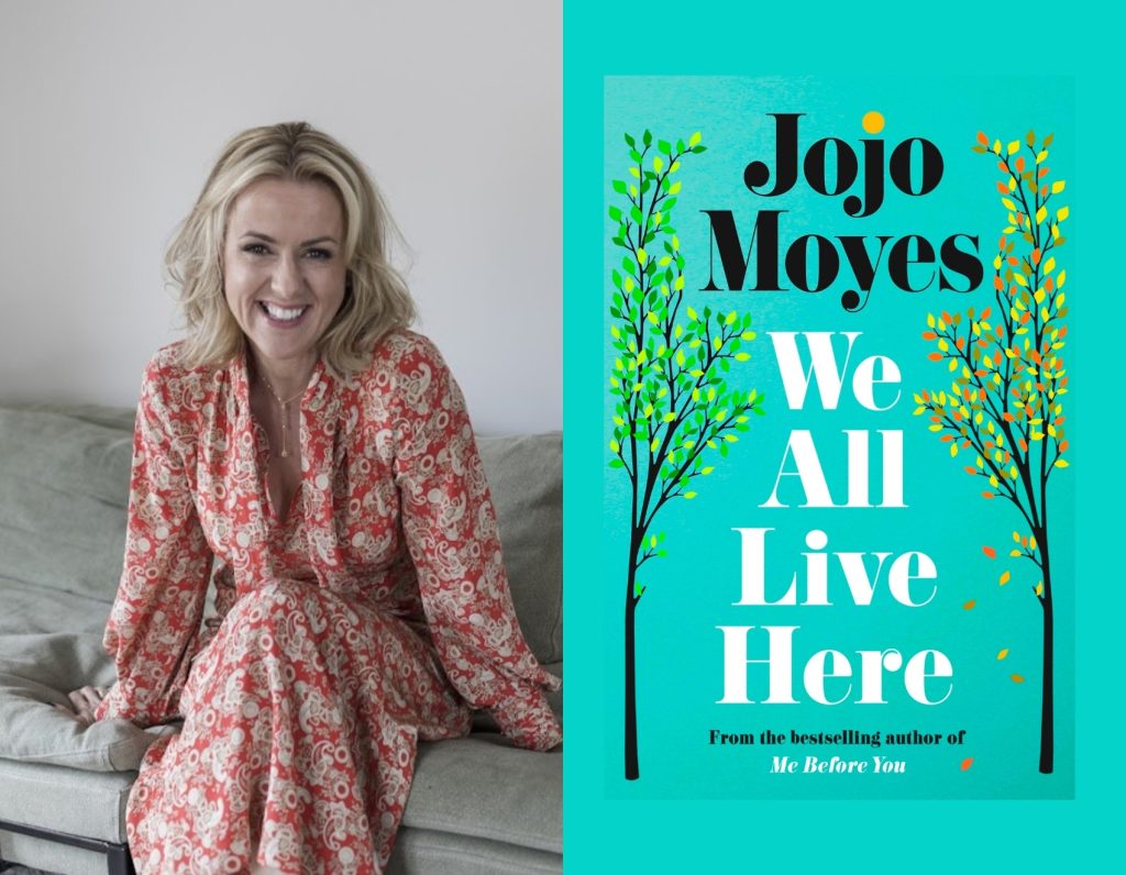 A smiling seated woman beside a green book cover