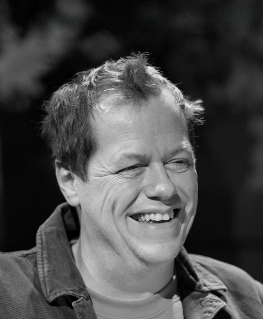 A smiling man wearing a shirt in black and white