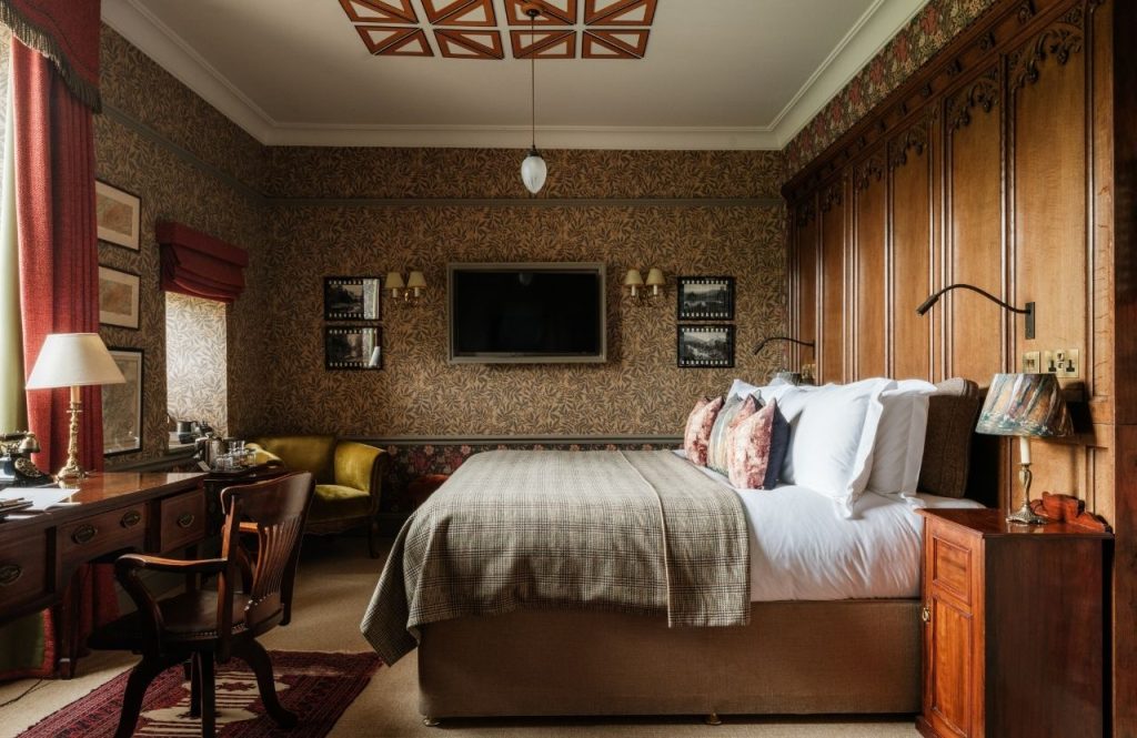 A bed viewed side on in a room with brown patterned wallpaper