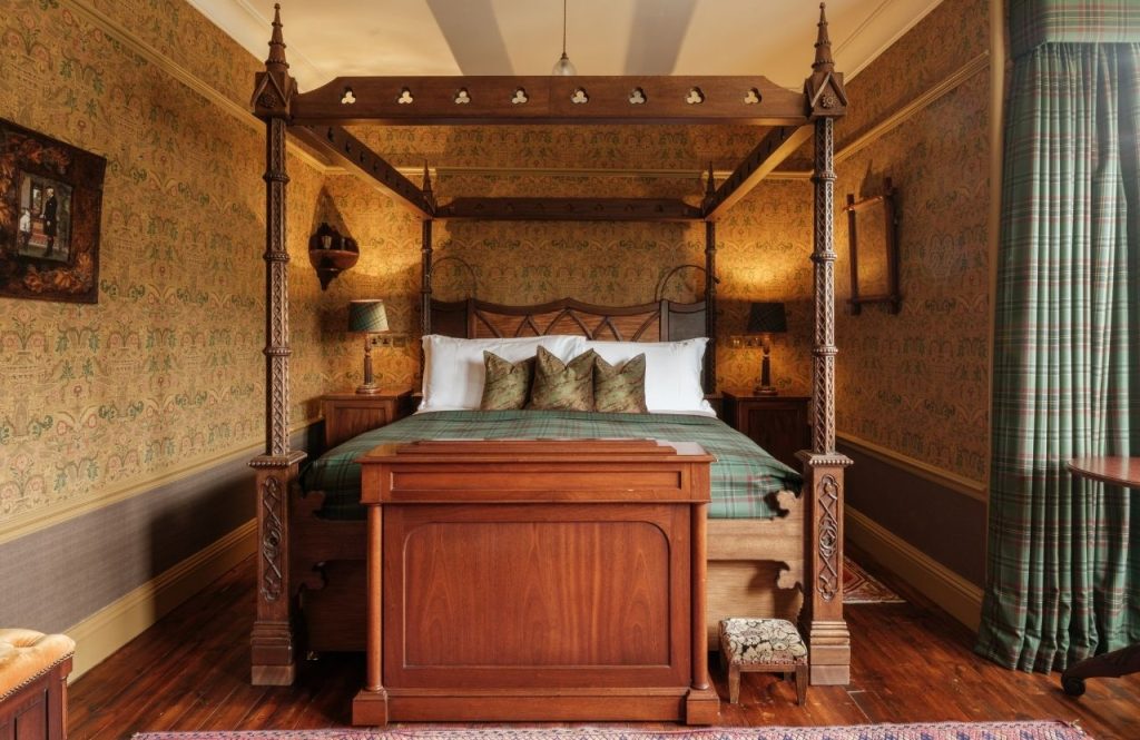 A four poster wooden bed in an opulent bedroom
