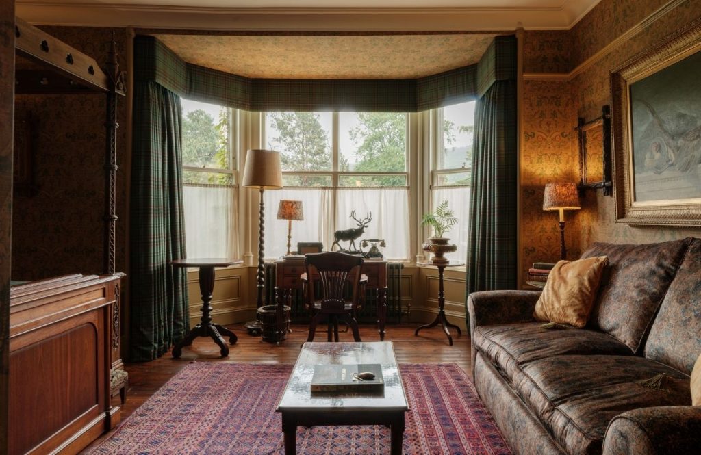 A bay window in an opulent Victorian bedroom with a sofa at the right