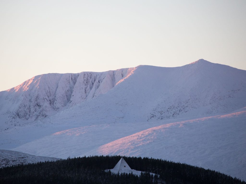 Mountains at dusk, covered in snow and a pink evening light