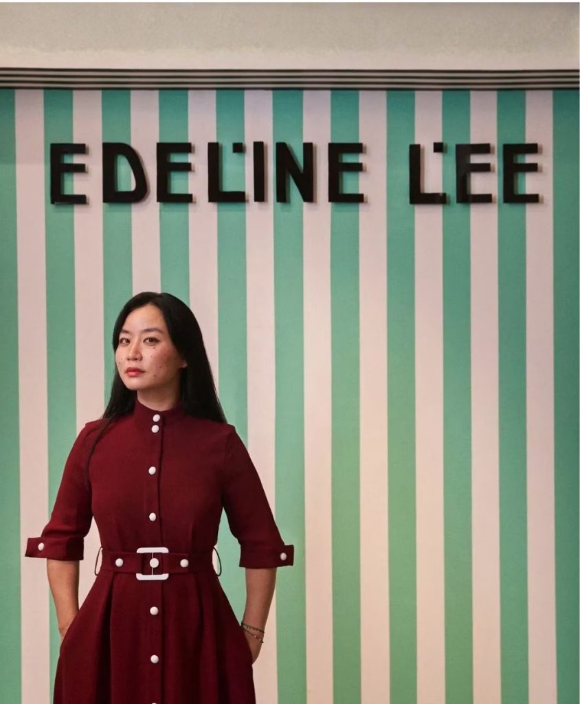 A woman in a red dress stood in front of a green and white striped backdrop.