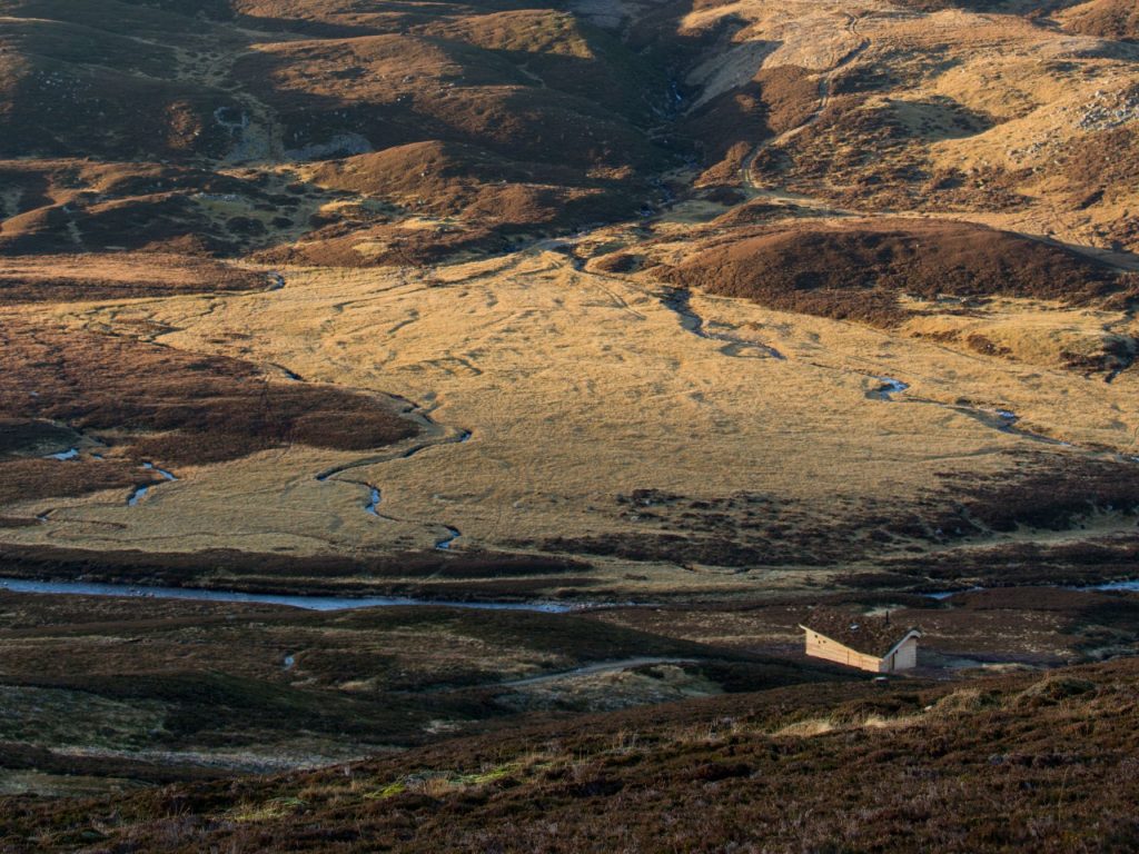 A wooden cabin in a wild landscape in the Scottish Highlands