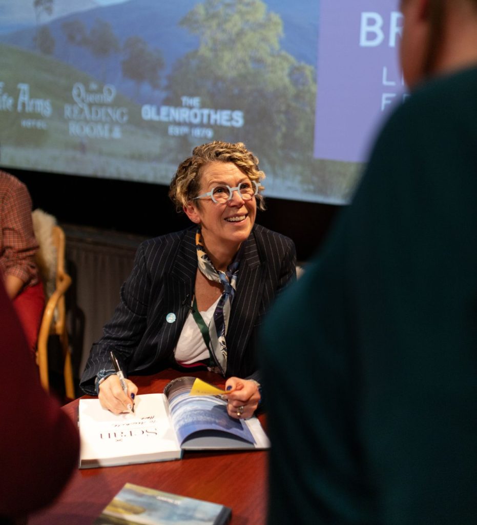 A smiling woman signing a book