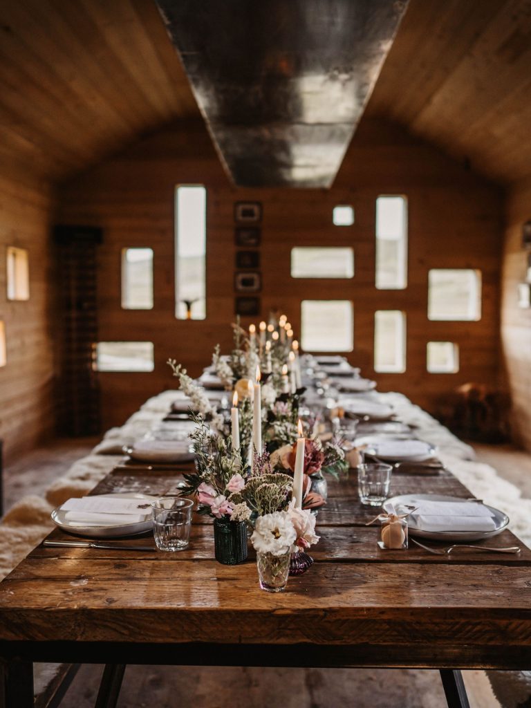 A minimalist cabin interior with a table set for dinner with flowers and candles