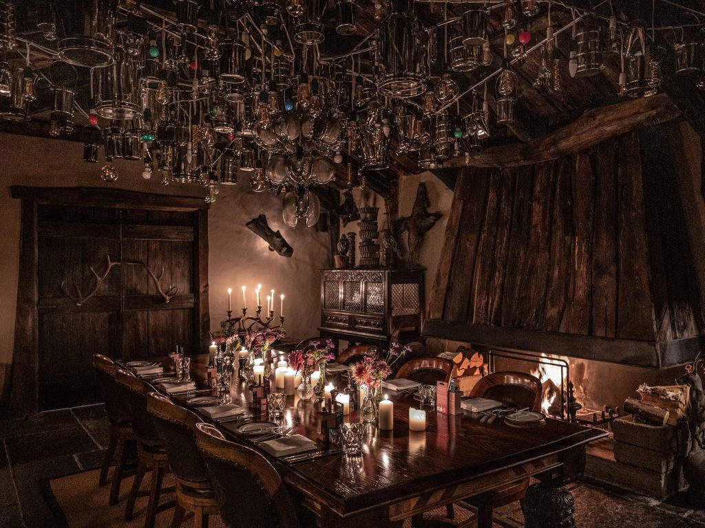 An atmospheric dining room with a large abstract chandelier overhead, lit by candlelight