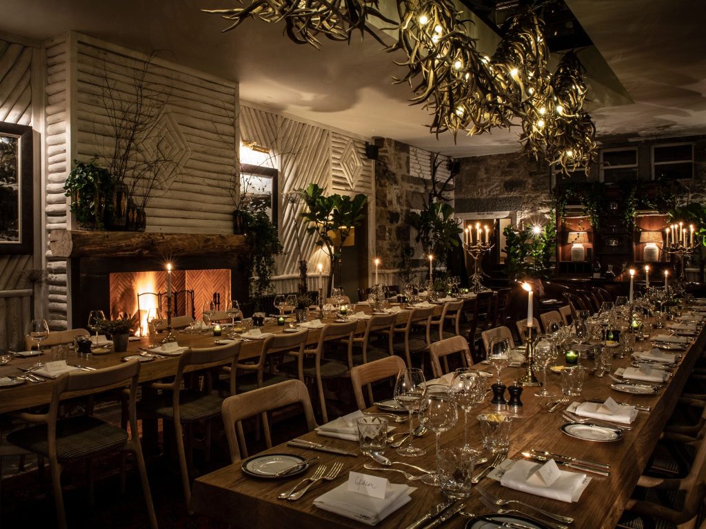Celebratory dining banquet tables in a dimly lit room with a fire