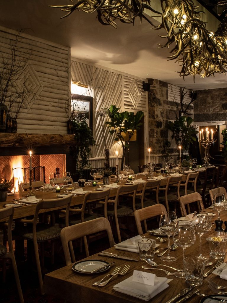 Celebratory dining banquet tables in a dimly lit room with a fire