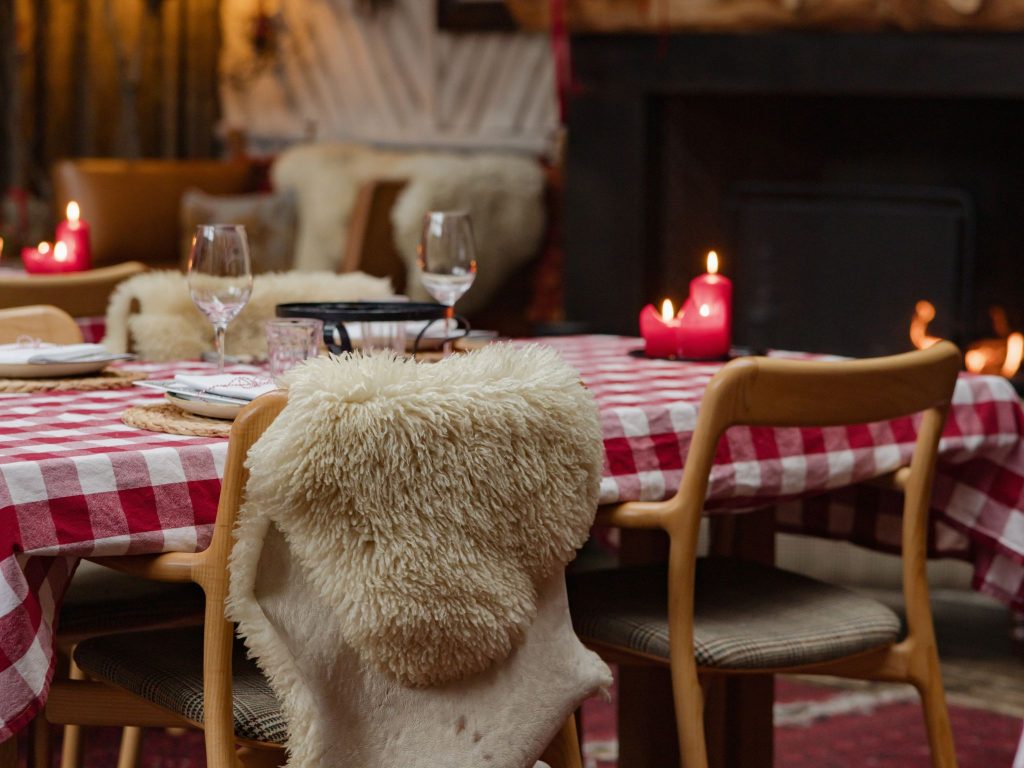 A table with a red gingham tablecloth in a wood panelled room with a fireplace